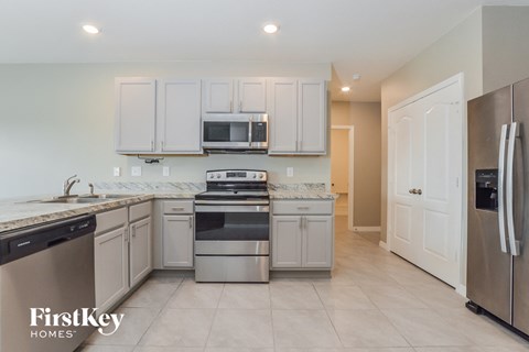 A kitchen with a refrigerator on the right and a sink on the left.