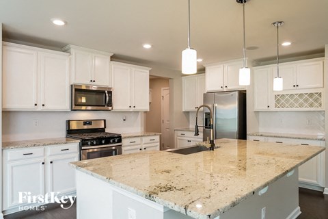 a white kitchen with granite counter tops and white cabinets