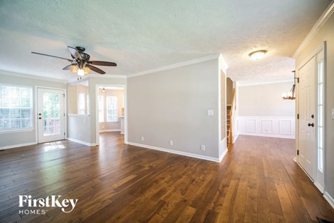 A spacious room with wooden floors and a ceiling fan.