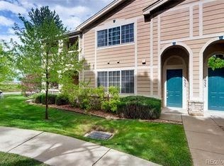 A beige building with a blue door and a tree in front.