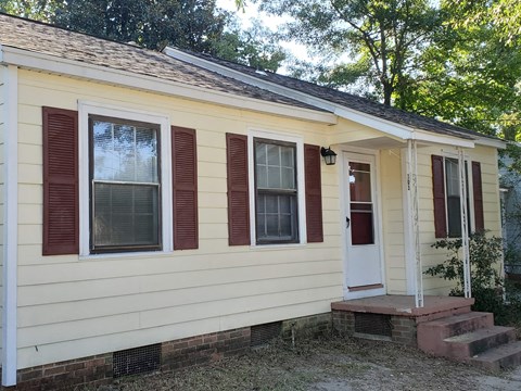 A small house with a red door and red shutters.