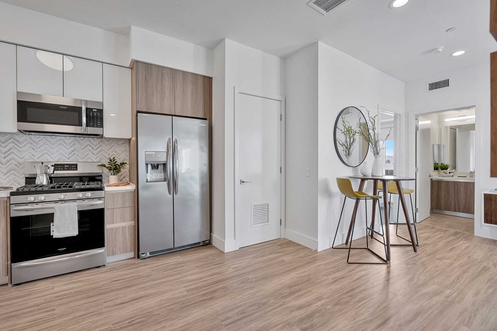 an open kitchen and dining room with a stainless steel refrigerator