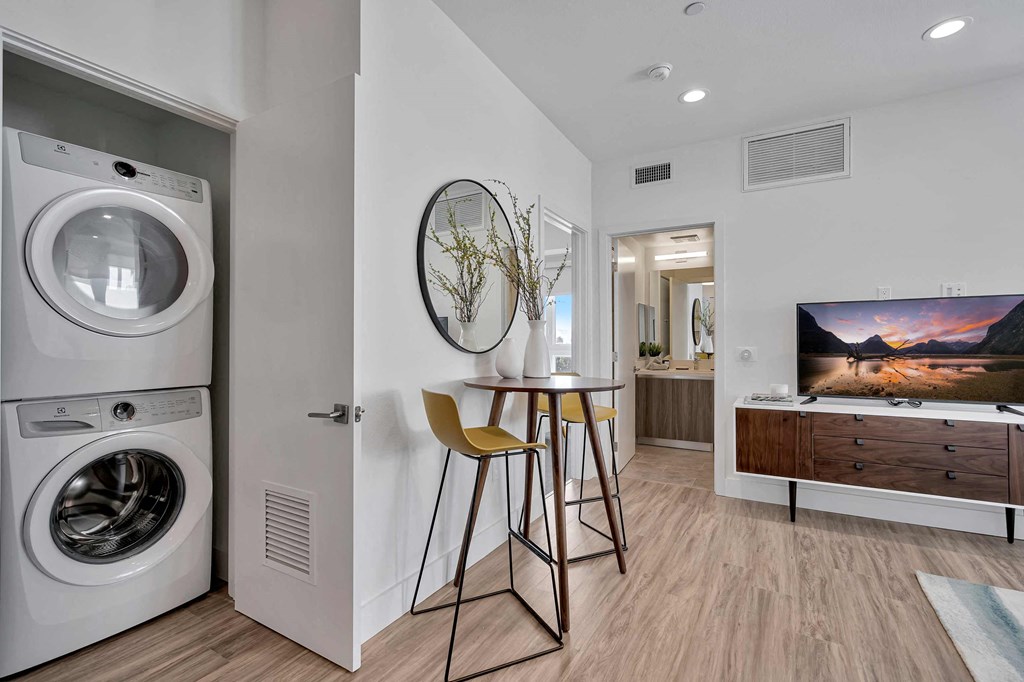 a living room with a washing machine and a table with a chair