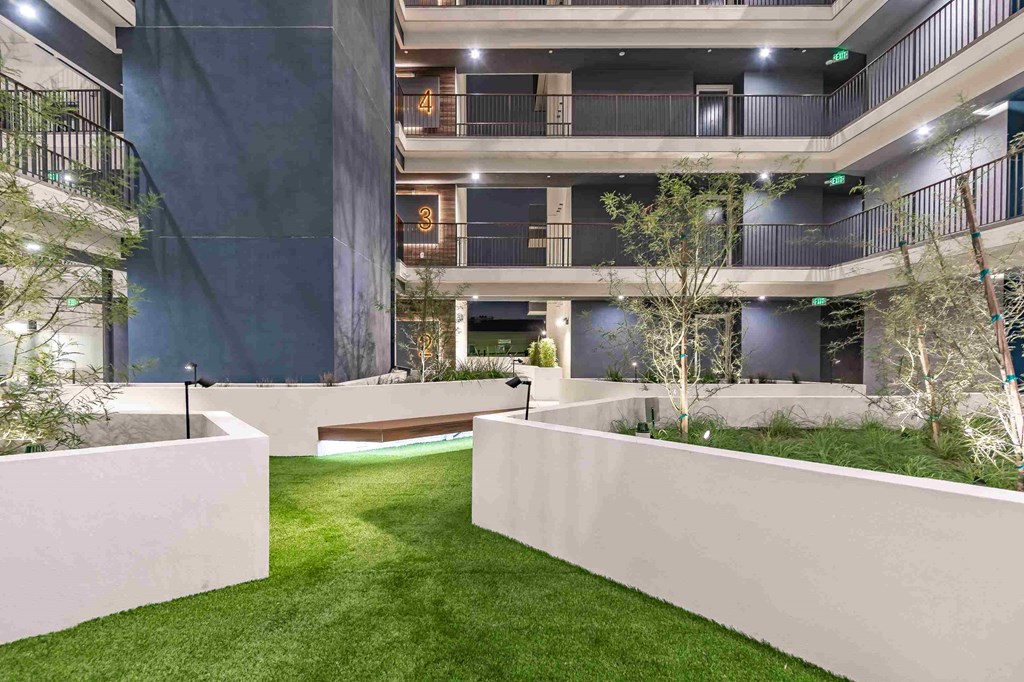 an open courtyard in an office building with grass and trees