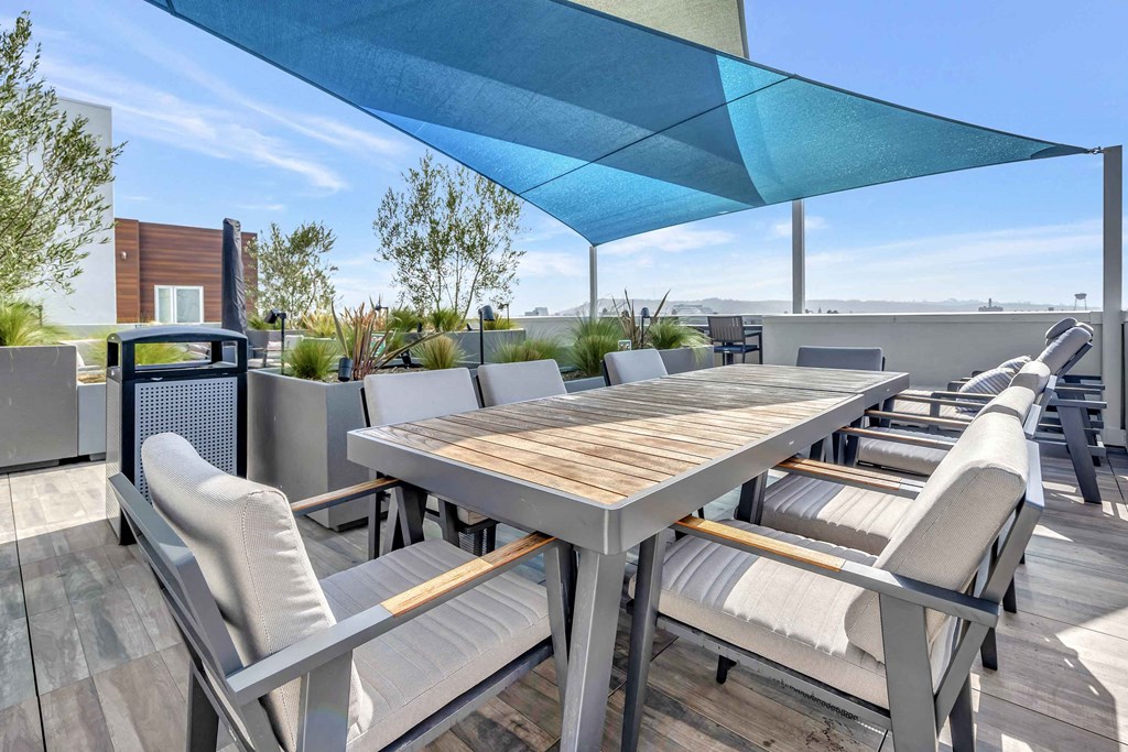 a dining area with a table and chairs under an umbrella