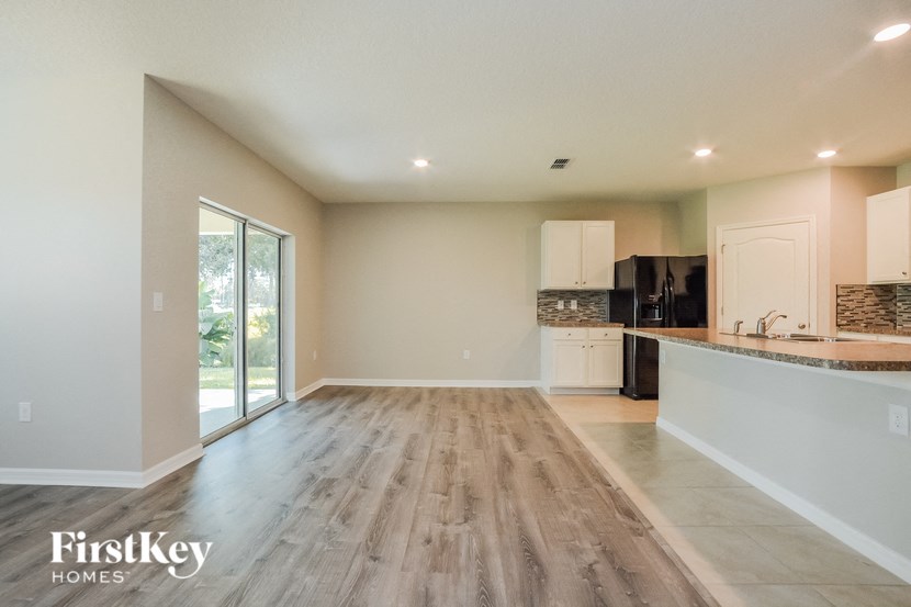 A spacious kitchen with wooden floors and a black refrigerator.
