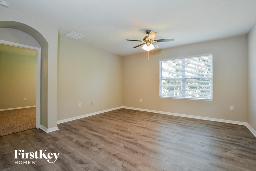 A spacious room with a ceiling fan and wooden flooring.