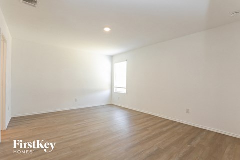 the living room of a home with white walls and wood floors