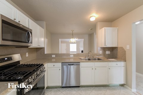 A kitchen with a stove top oven, microwave, dishwasher, and double sink.