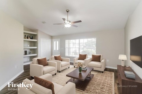 A living room with a brown couch and a white ceiling fan.