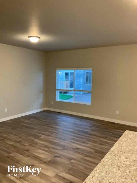 an empty living room with a window and wood floors
