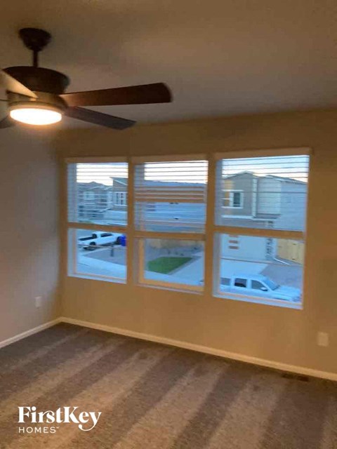 a living room with three windows and a ceiling fan