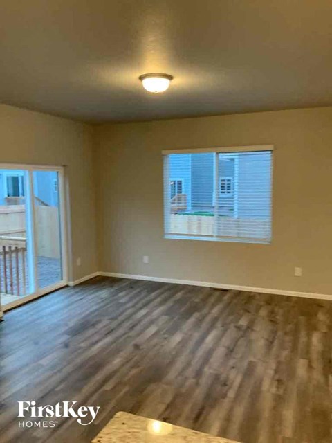 an empty living room with wooden floors and a window