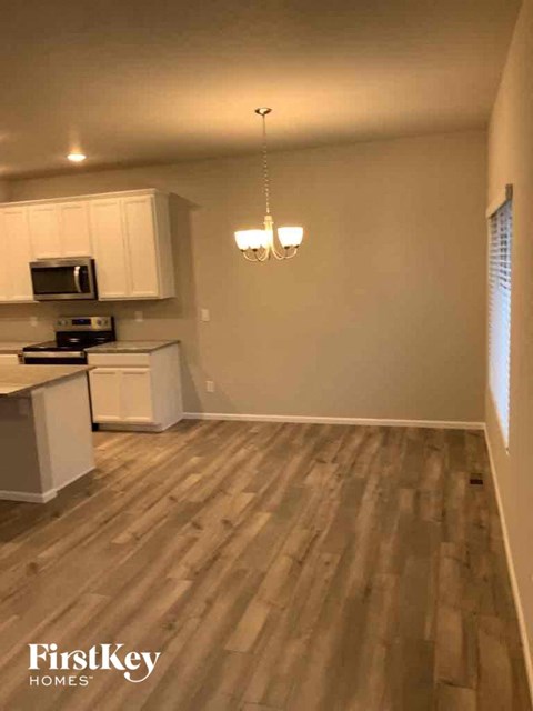 an empty kitchen with wooden floors and white cabinets