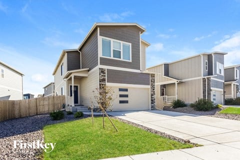 a beige and gray house with a driveway and lawn