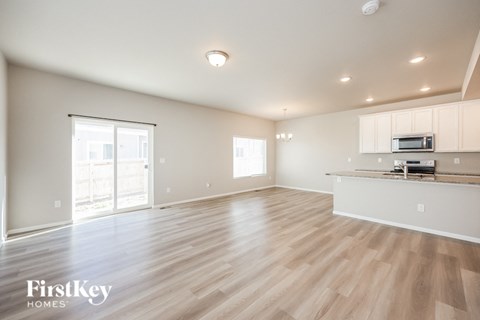 the living room and kitchen of an empty house with wood flooring