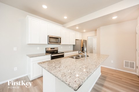 a kitchen with white cabinets and a granite counter top