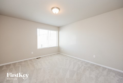 the spacious living room with white carpet and a window