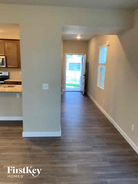 a hallway with a hard wood floor and a door to a kitchen