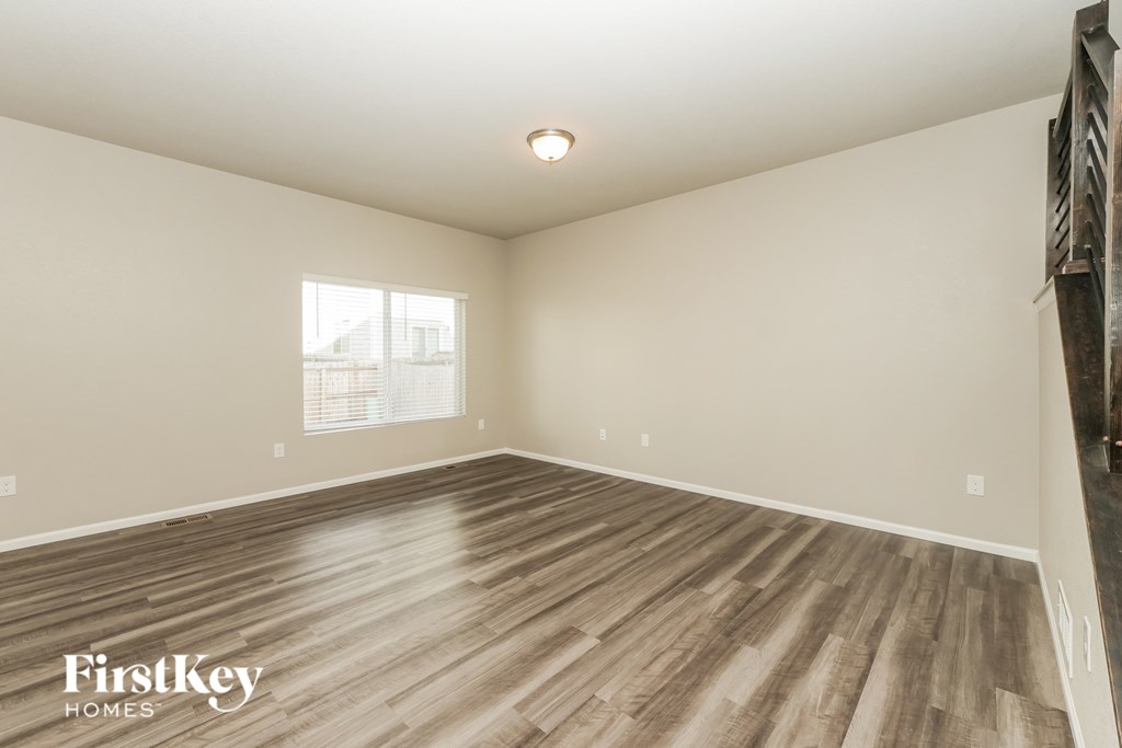 A room with wooden flooring and a window with blinds.