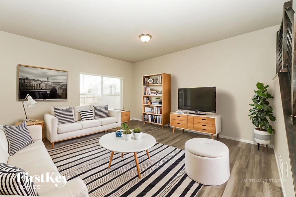 A living room with a white couch, a coffee table, a television, and a bookshelf.