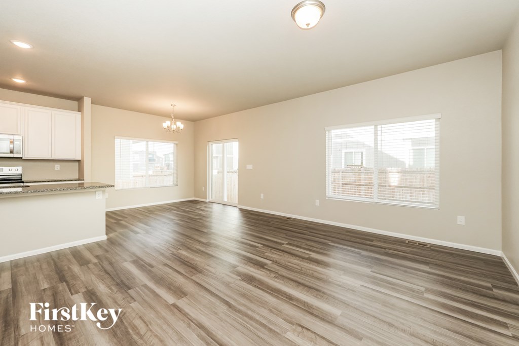 A spacious room with wooden flooring and a kitchen area to the left.