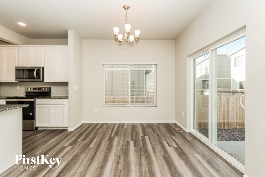 A well-lit, spacious kitchen with wooden flooring and a chandelier.