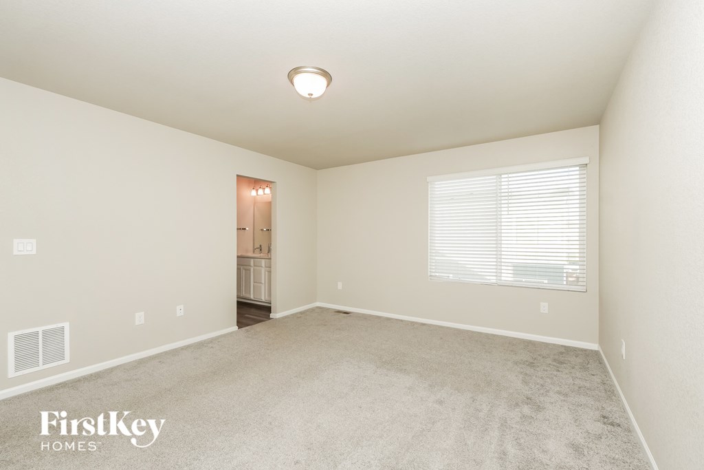 A spacious empty room with a carpeted floor and a door leading to another room.