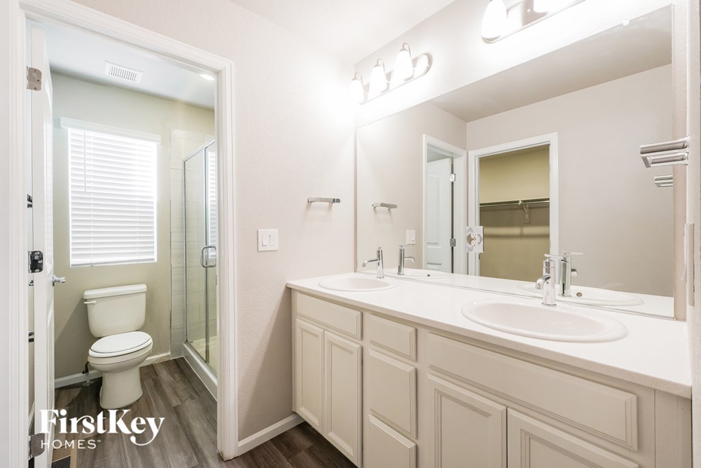 A white bathroom with a toilet, sink, and mirror.