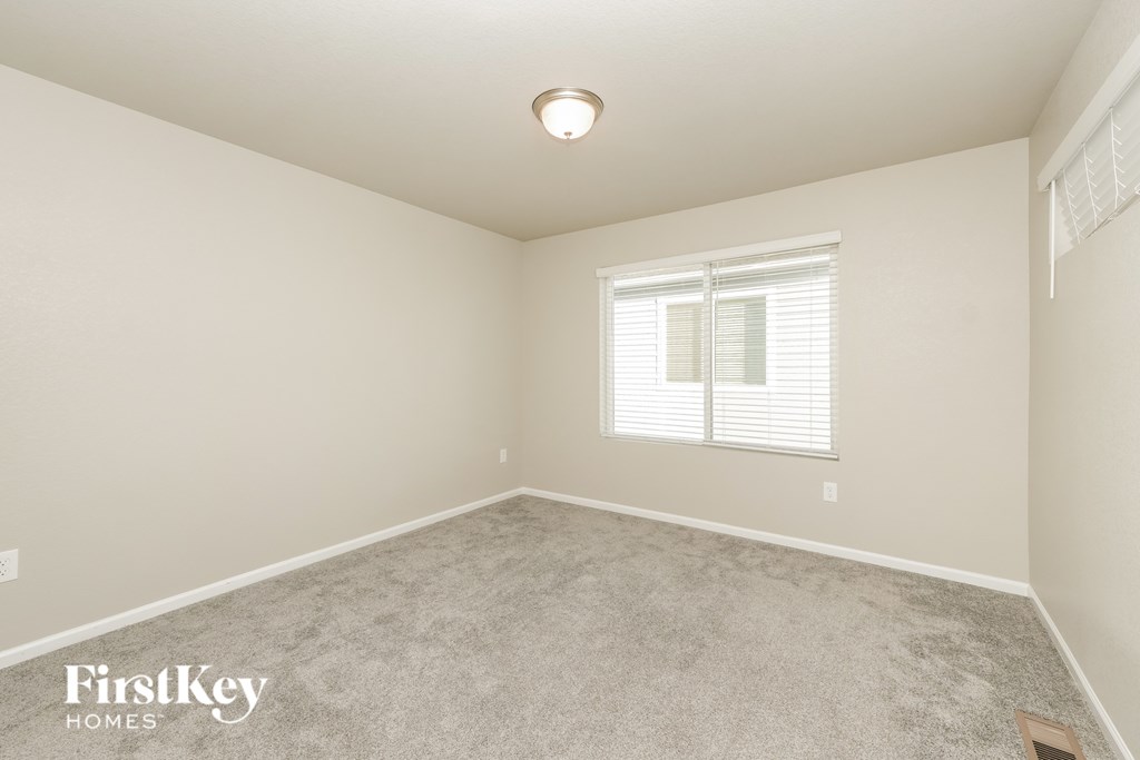 A room with a carpeted floor and a window with blinds.