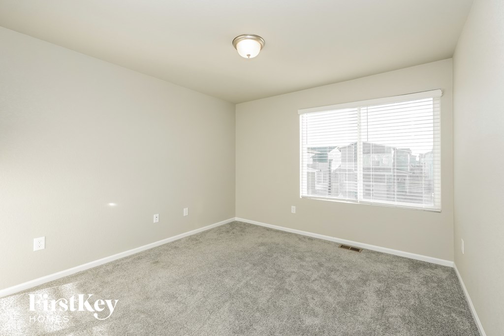 A room with a carpeted floor and a window with blinds.