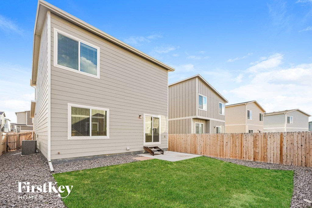 A house with a grey siding and a brown fence is shown.