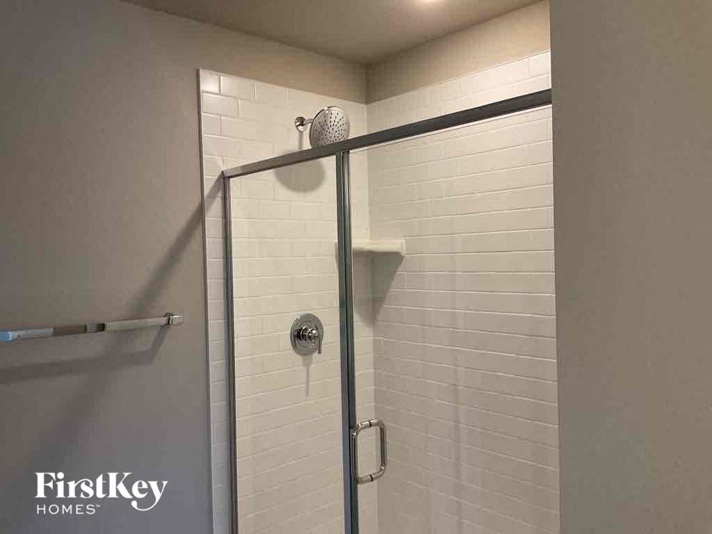 a white tiled shower with a glass door