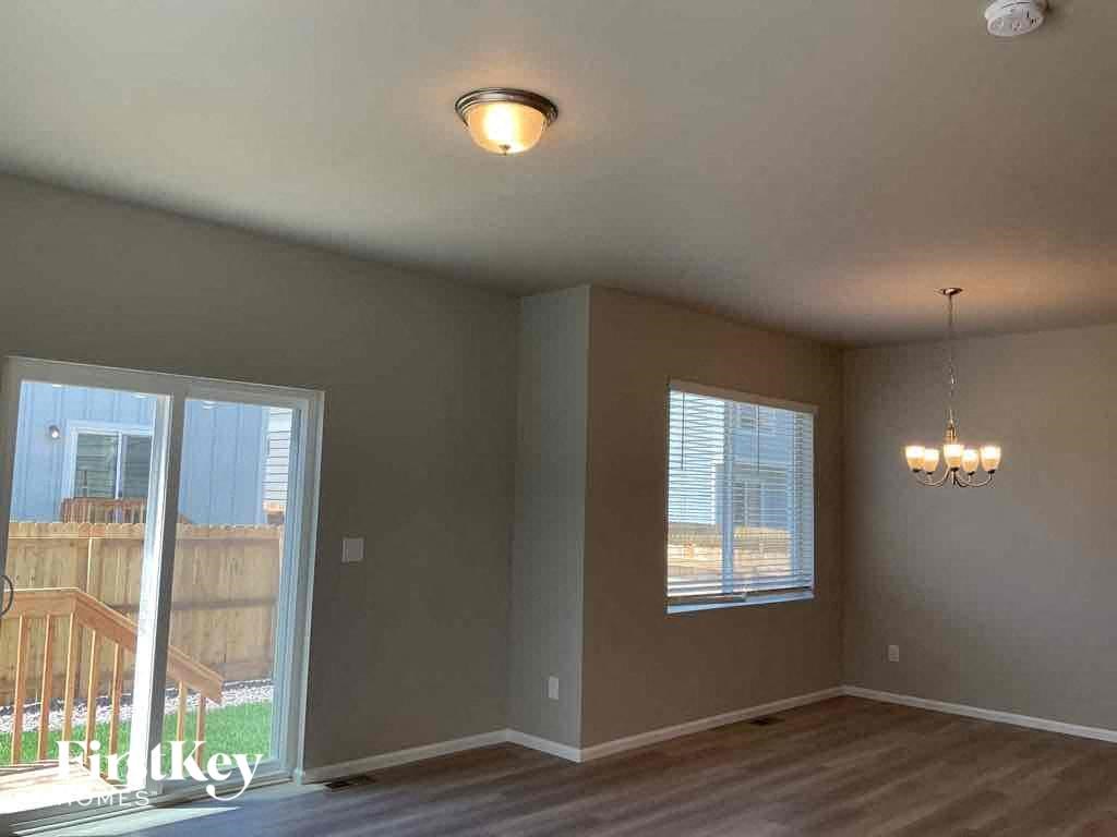 an empty living room with a sliding glass door to a balcony