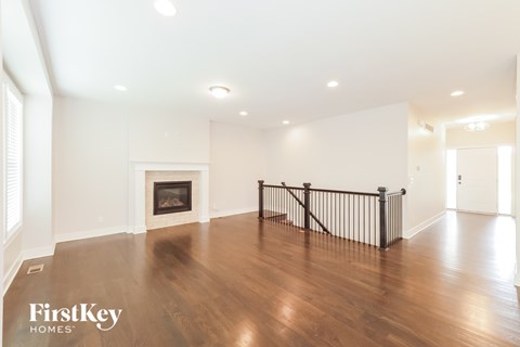 A spacious living room with a fireplace and wooden floors.