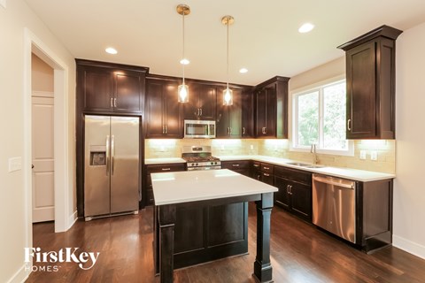 A modern kitchen with dark wood cabinets and stainless steel appliances.