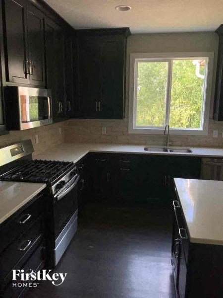 A kitchen with black cabinets and a stove top oven.