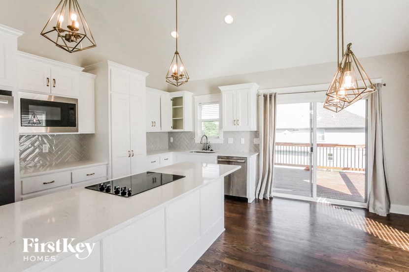a kitchen with white cabinets and stainless steel appliances and a balcony