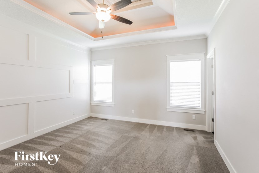 an empty room with a ceiling fan and two windows