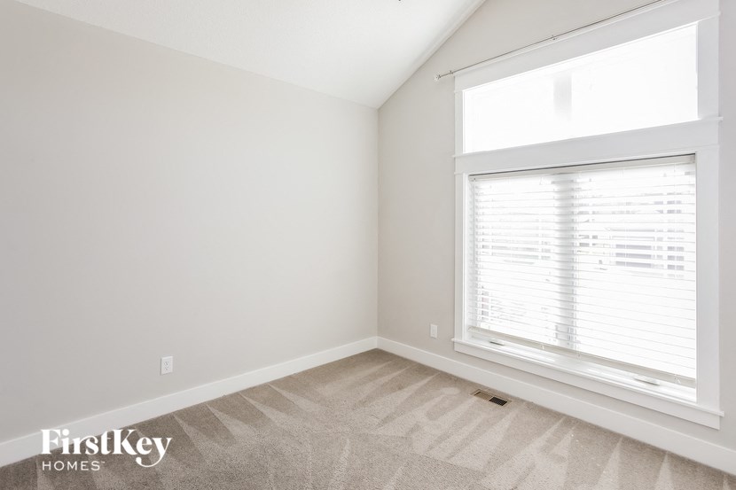 a bedroom with a large window and white walls