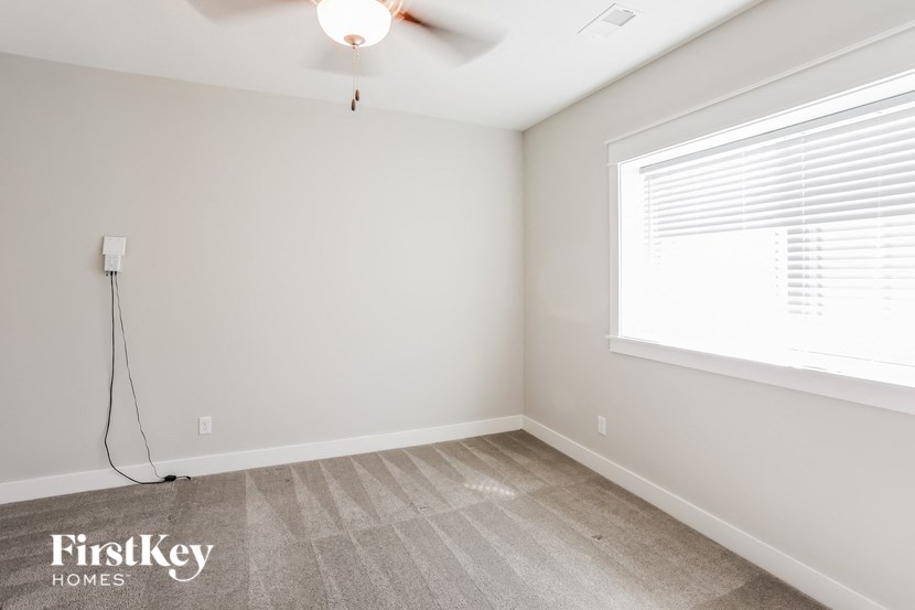 a bedroom with a ceiling fan and a large window