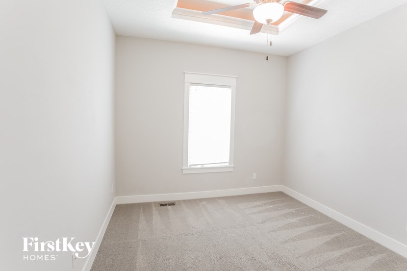 a clean and empty room with a ceiling fan and a window