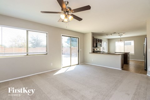 A spacious living room with a ceiling fan and sliding glass doors.