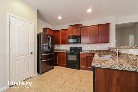 A kitchen with brown cabinets and a granite counter top.