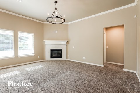 an empty living room with a fireplace and a chandelier