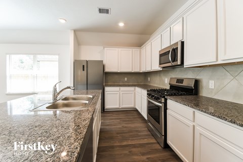 A kitchen with a granite countertop and stainless steel appliances.