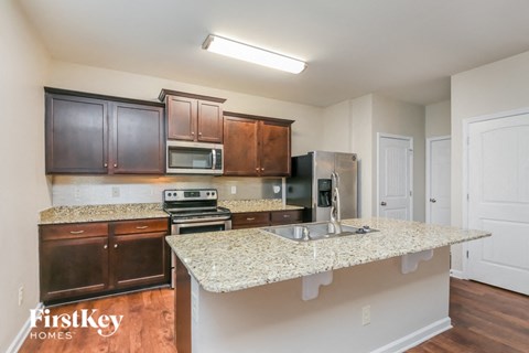 A kitchen with a granite countertop and wooden cabinets.