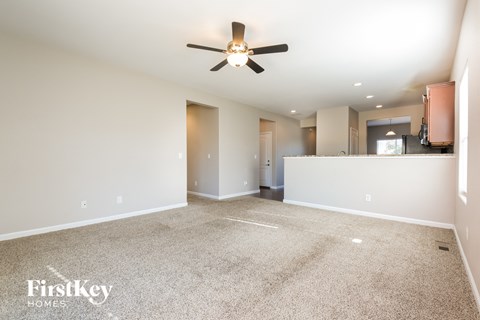 a spacious living room with carpet and a ceiling fan