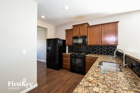 a kitchen with black appliances and granite counter tops and wooden cabinets