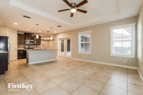 A spacious kitchen and living room with a ceiling fan and lighting fixtures.